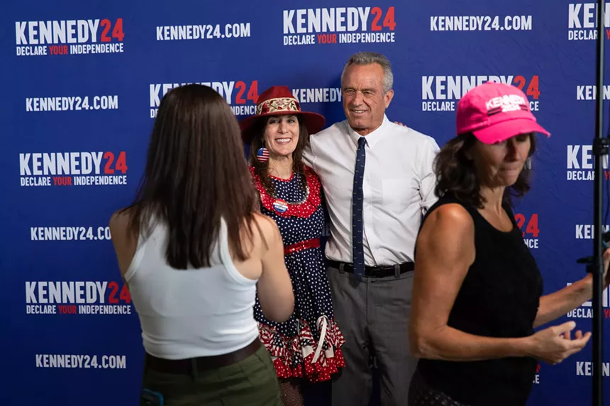 man in white shirt takes photo with woman