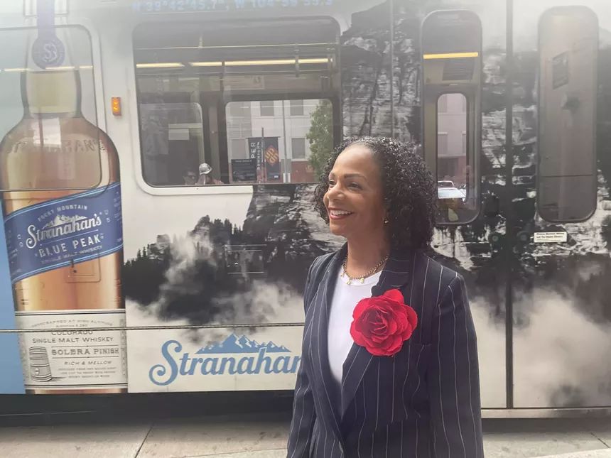 Woman in suit stands in front of light rail
