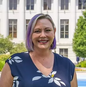 Blonde woman stands in front of white building