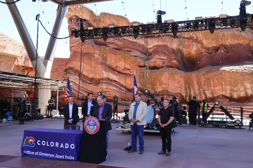 GOvenror Jared Polis signs a bill at Red Rocks Ampitheatre