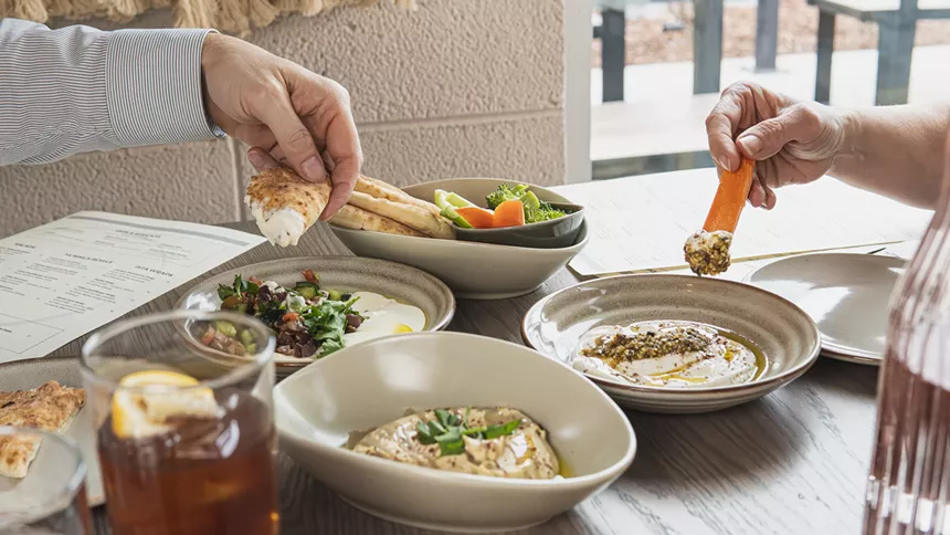 Diners dipping pita and veggies into hummus at Boychik