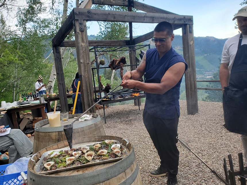 a man standing outside next to a platter of oysters