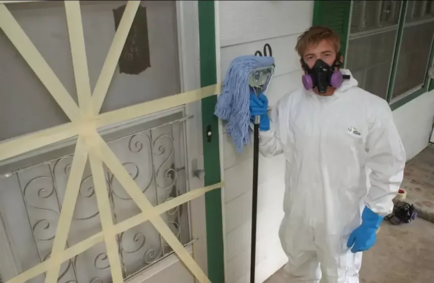 Man in rubber suit with gas mask and mop