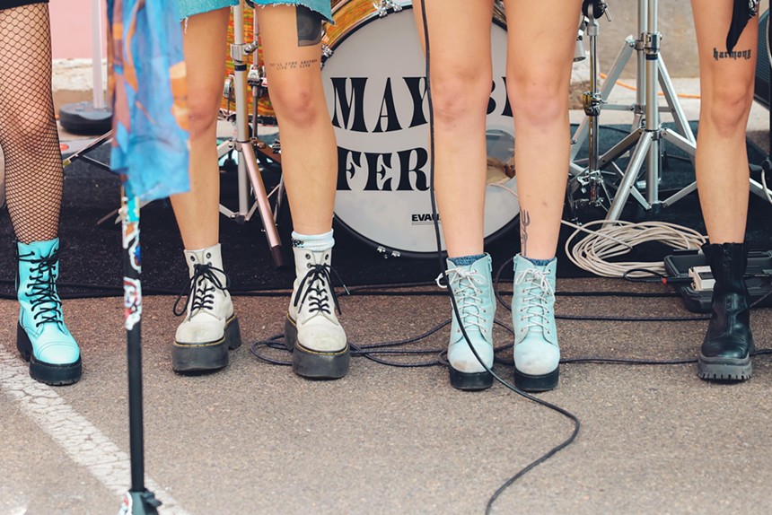 four women wearing boots in front of a drum set