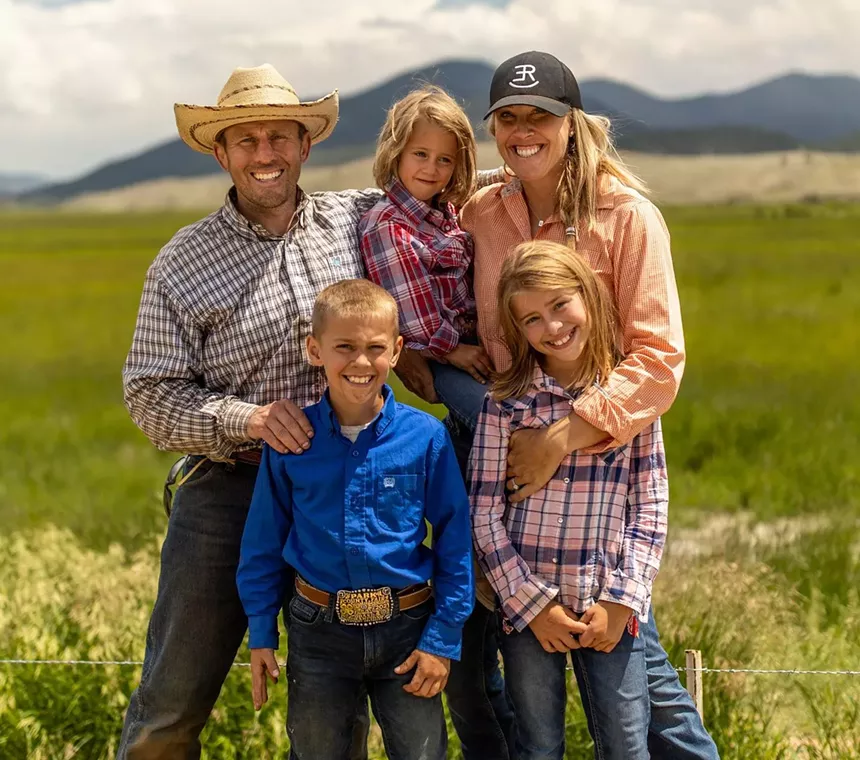 man in cowboy hat and woman in baseball cap posing outside with three children