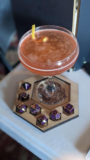 Dungeons and Dragons dice  next to a cocktail