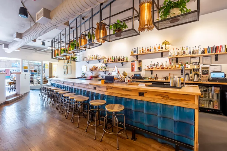 empty stools lined up in front of a blue bar