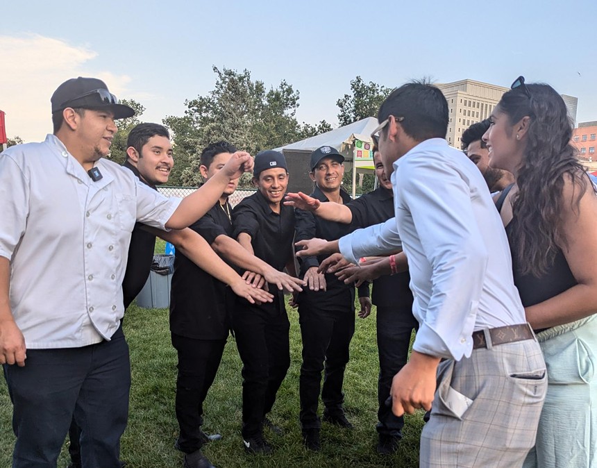 a group of people in chef's coats reaching their hands in for a group high five