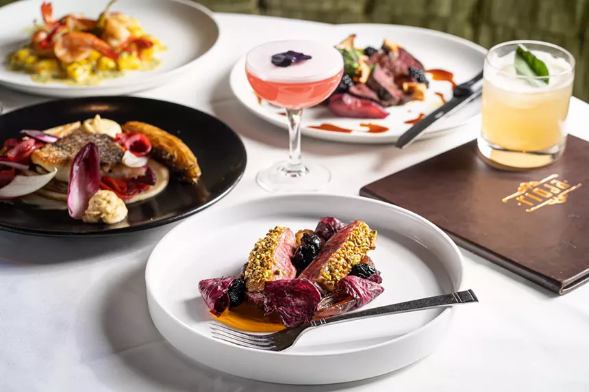 a pink cocktail and various foods on white plates