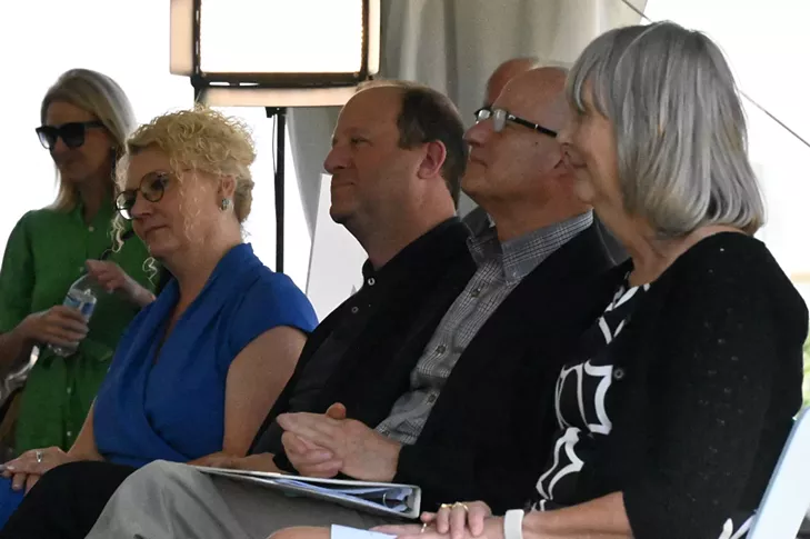 Four people sit and listen to a person talk.