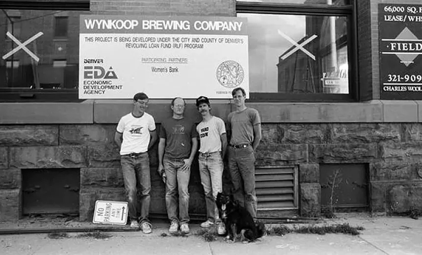 black and white photo of four menu standing in front of a building