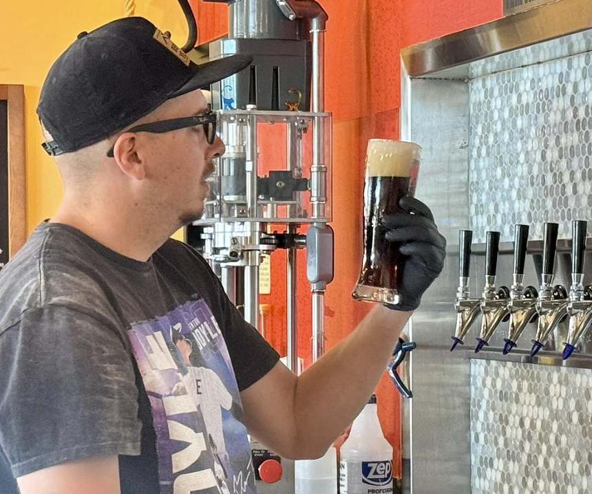 Brewer holding a beer in front of the taps.