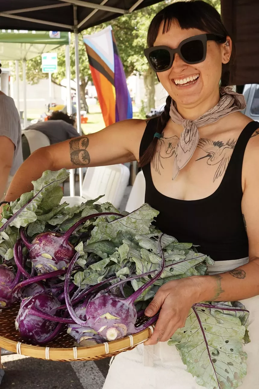 woman carrying a box of purple kohlrabi.
