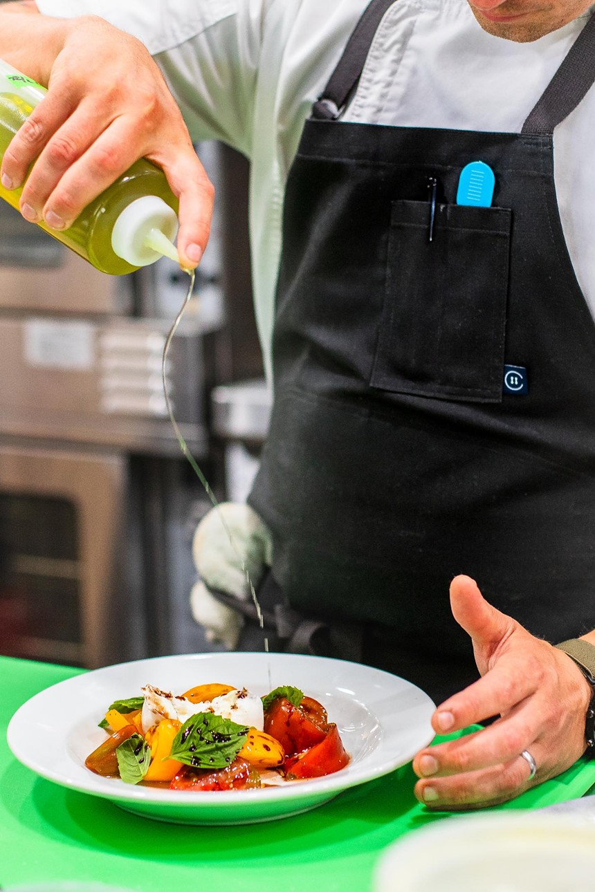olive oil being drizzled on a caprese salad
