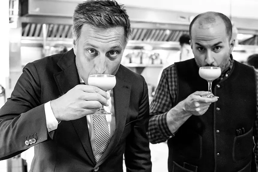 black and white photo of two men sipping cocktails
