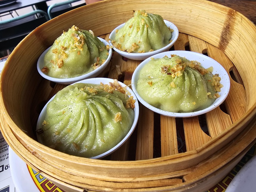 light green soup dumplings in a wooden steamer basket