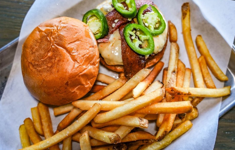 a burger topped with jalapenos and fries