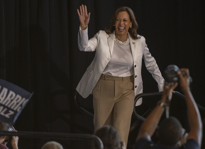 woman in white jacket waves