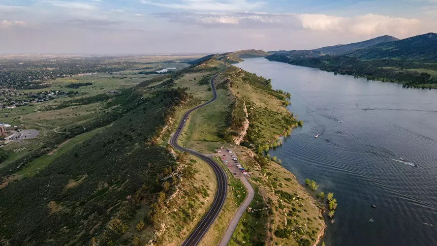 Horsetooth Reservoir spanning along the foothills, with a paved vehicle road to its left