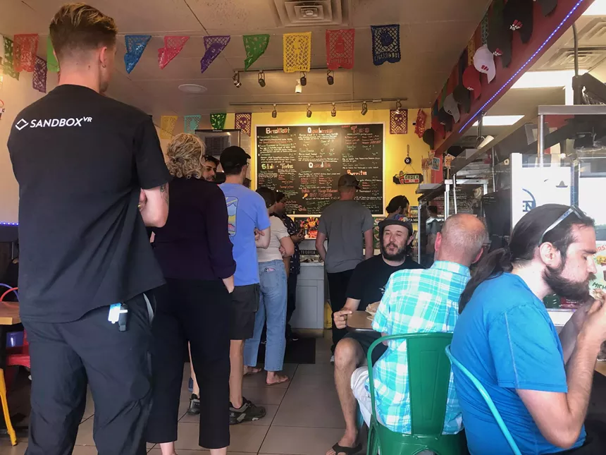 people standing in line inside a small restaurant