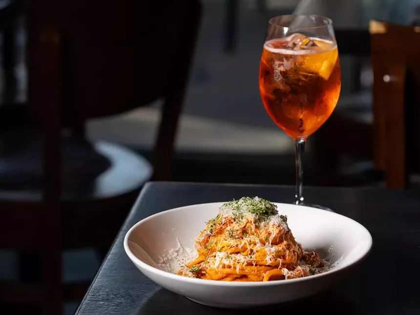 a plate of pasta and a cocktail in a wine glass