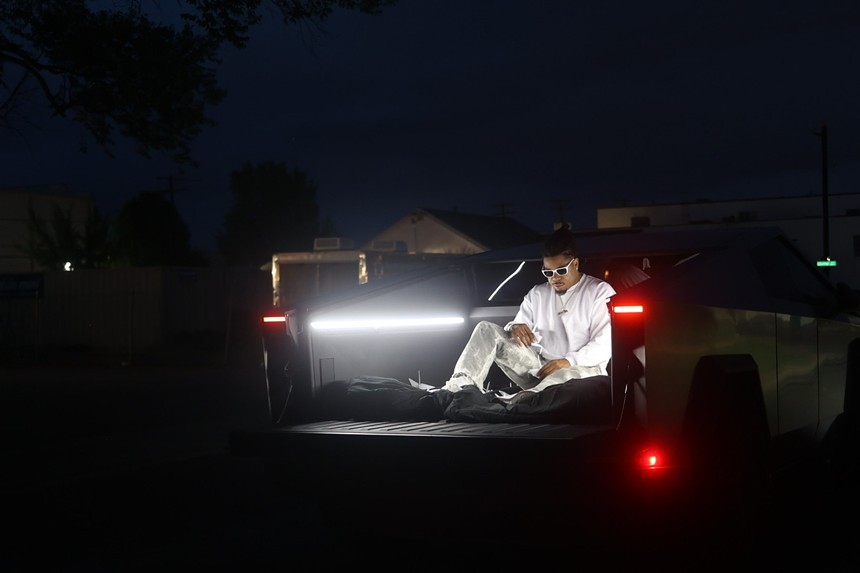 rapper sitting on the trunk of a car