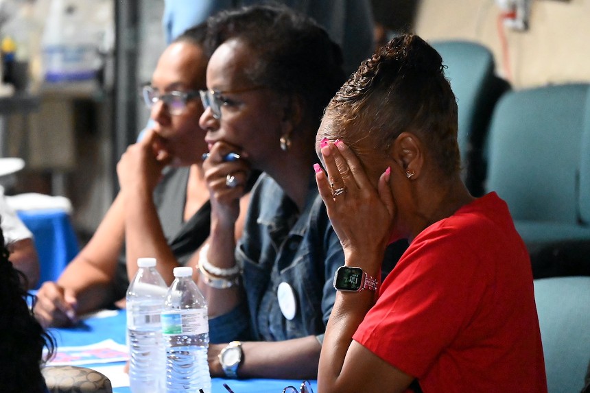 A woman covers her face while two other listen.