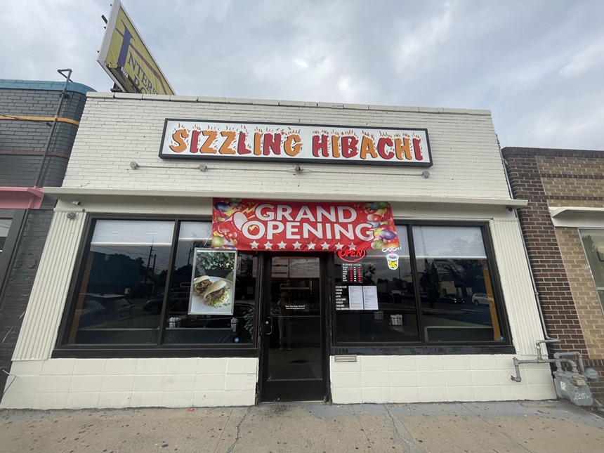 exterior of a tan building with a "grand opening" sign