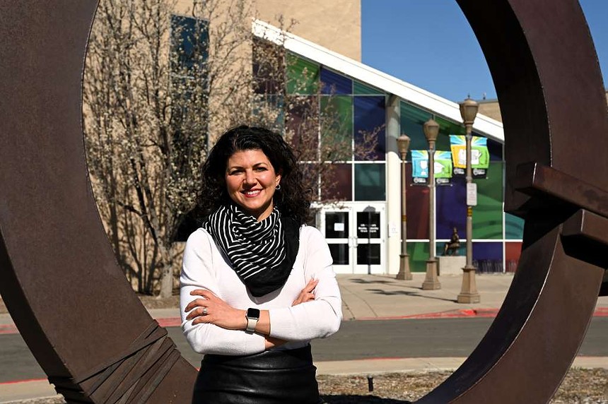 woman in white sweater in front of building.