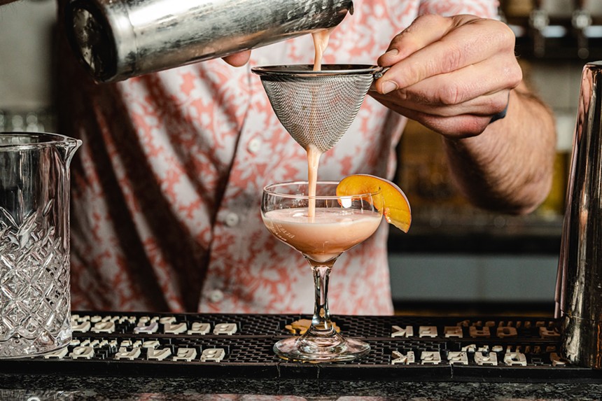 a occktail being strained into a glass