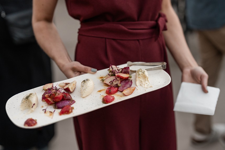 A woman in red holding a family-style course served during Harvest Week