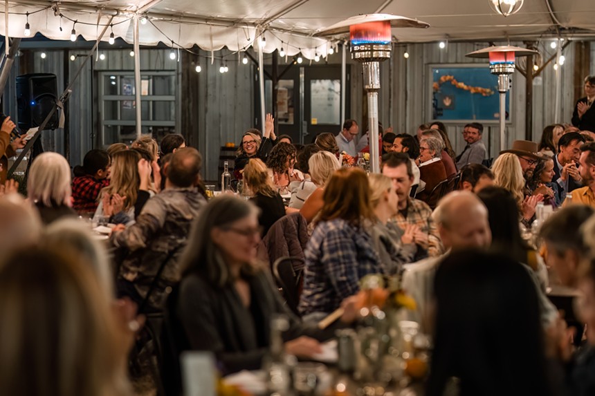 Dozens of people seated outdoors during a Harvest Week dinner