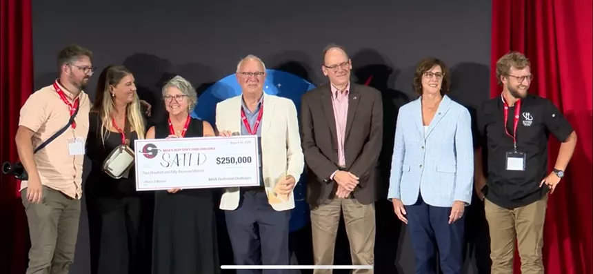 people on stage holding a large check