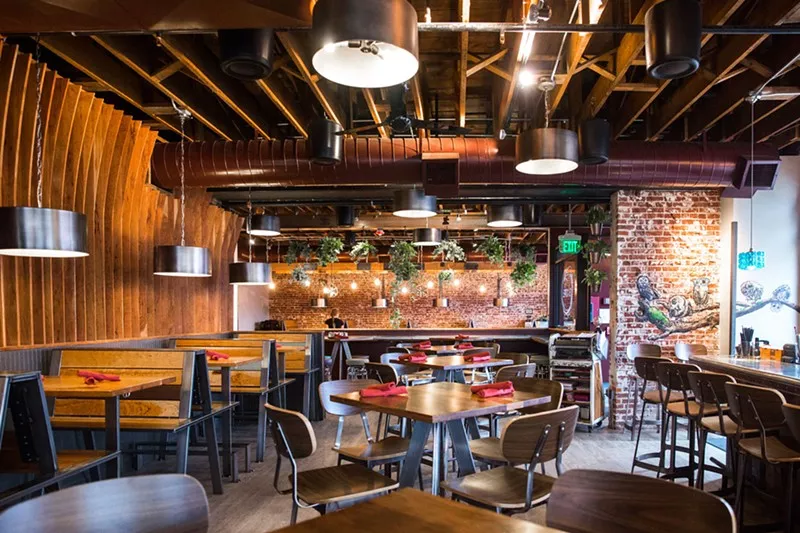 The modern interior of Acova featuring wood tables and exposed brick