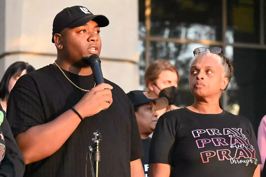A man speaks at a protest and a woman looks at him.