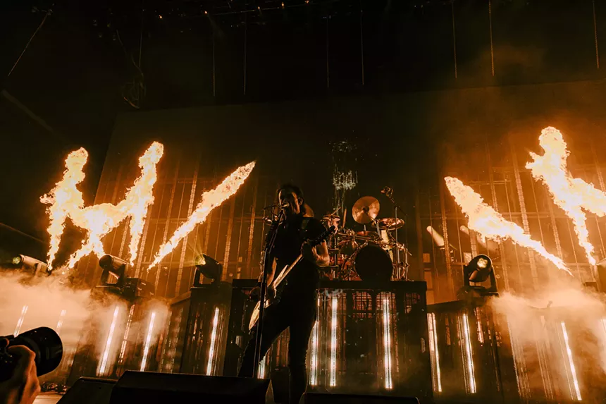 A singer playing the guitar in front of pyro.