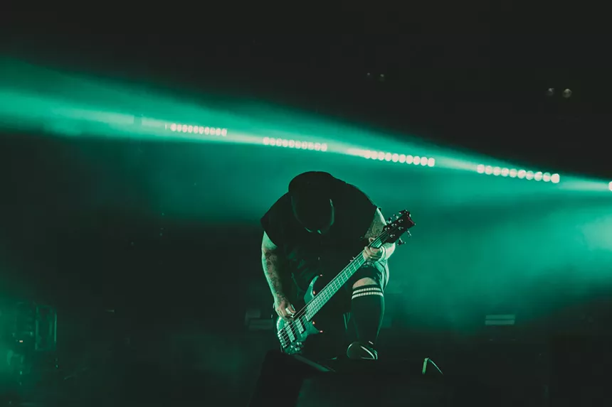 a bass player performing in front of a green strobe light.