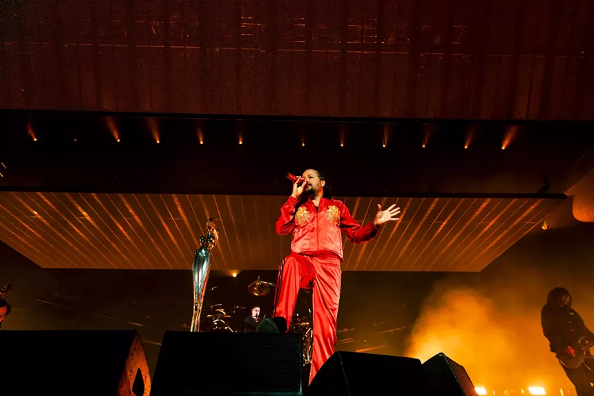 a man holding a microphone in front of a large stage design.