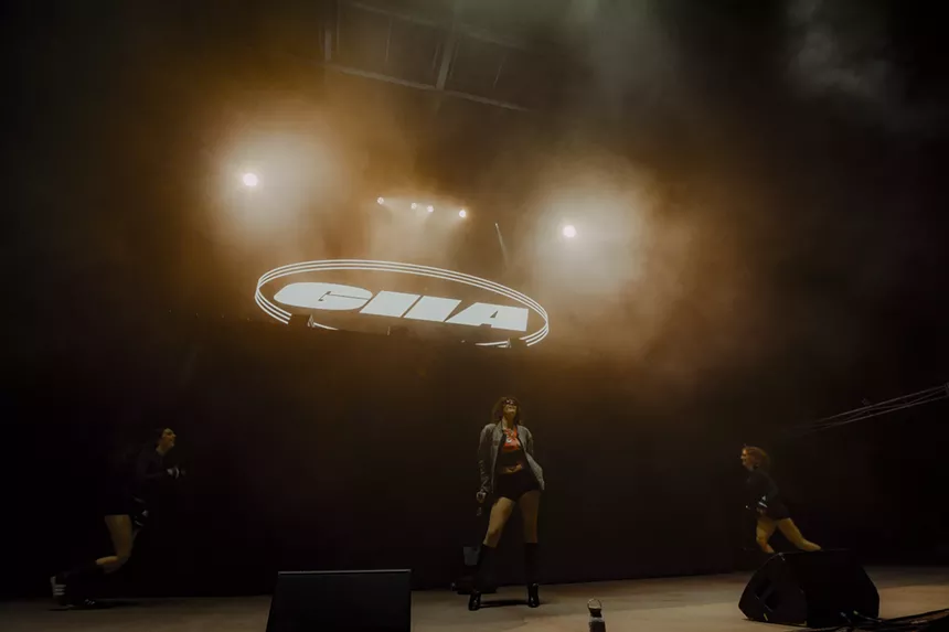 A photo showing the artist Evan Giia in front of a large stage with her name in lights.