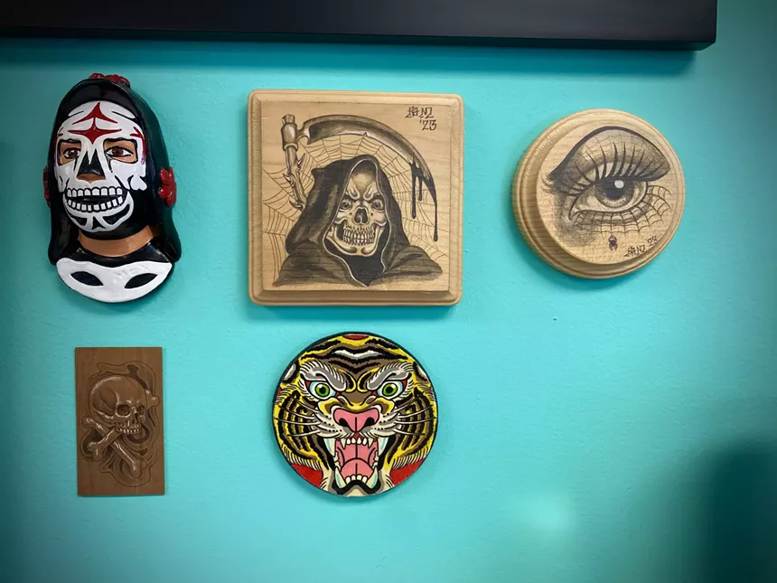 A shot of various artworks hanging on the wall at Skull and Dagger Tattoo Co.