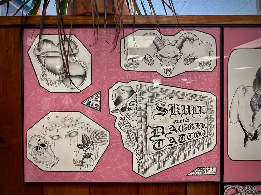 A shot of tattoo flash hanging on the wall at Skull and Dagger Tattoo Co.
