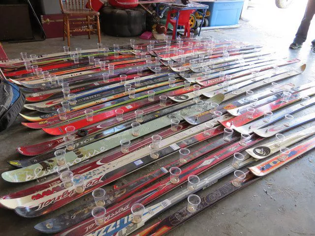 Dozens of skis affixed with plastic cups laying on a garage floor
