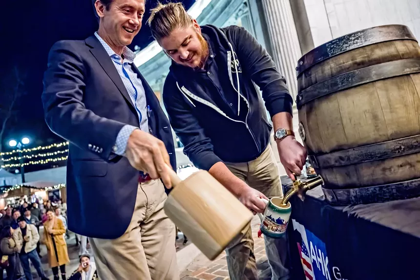 Two men tapping a wooden keg.