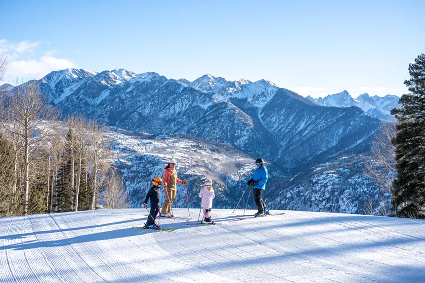 Children and adult skiers backdropped by snowy mountains at Purgatory Resort