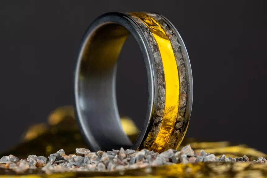A black wedding band with a gold strip down the middle