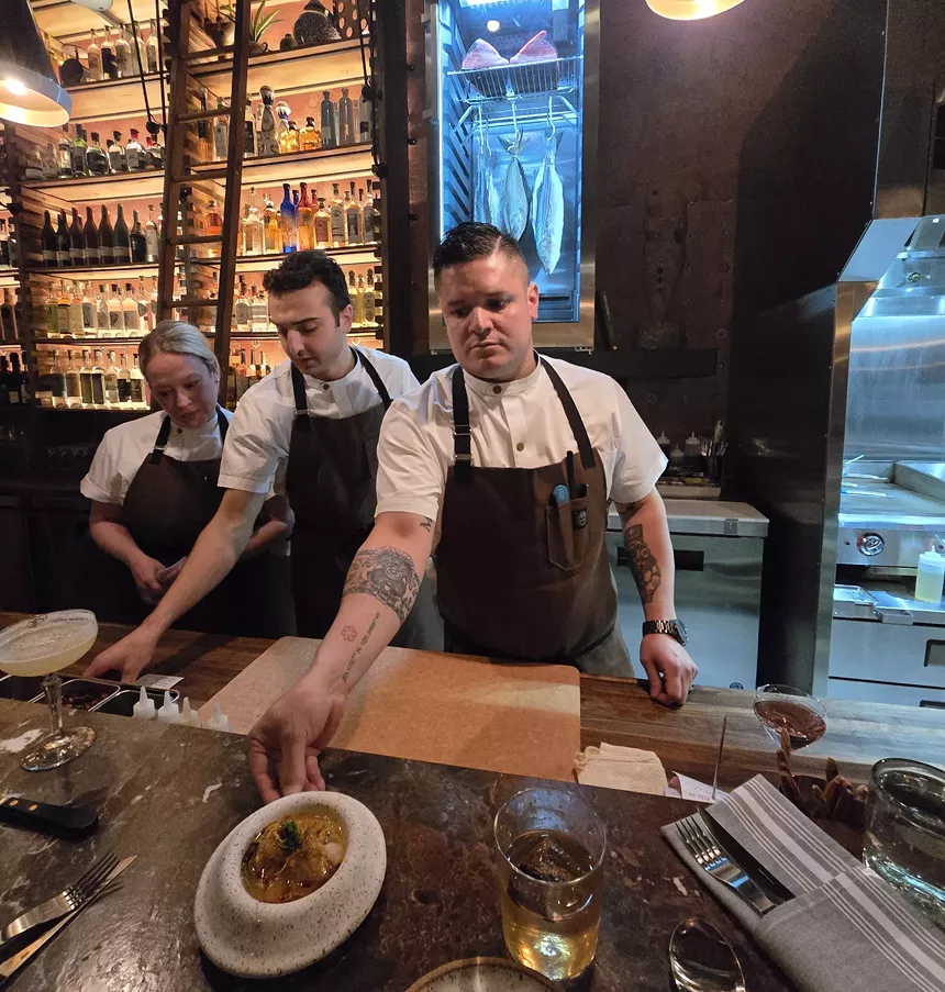 chefs in aprons serving food from behind a counter