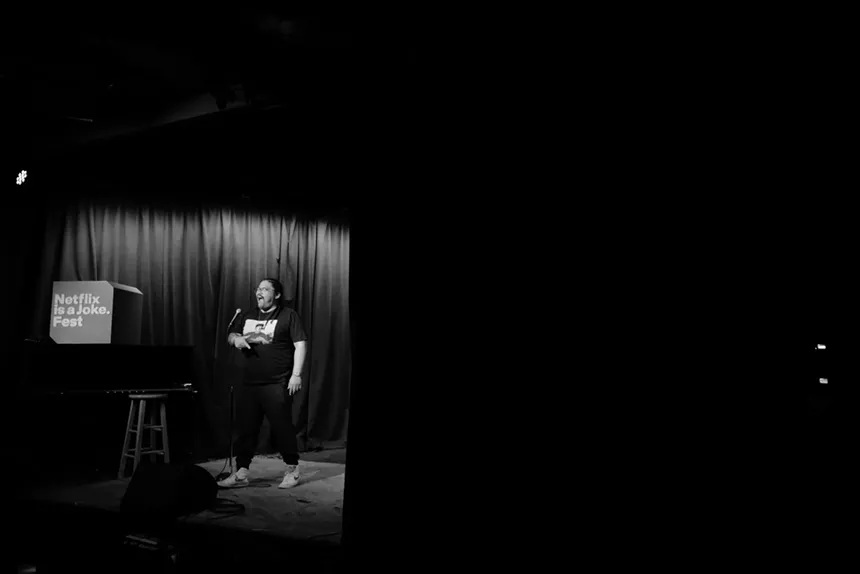 A black and white image of a man performing on stage.