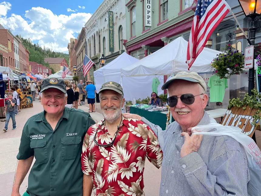three men with beer in mountain town.