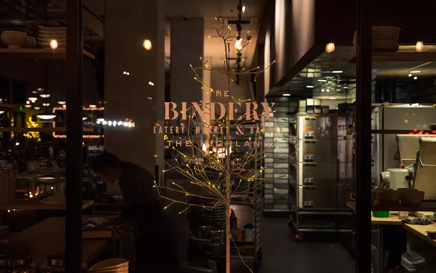 A window into the dimly-lit Bindery dining room decorated with holiday lights