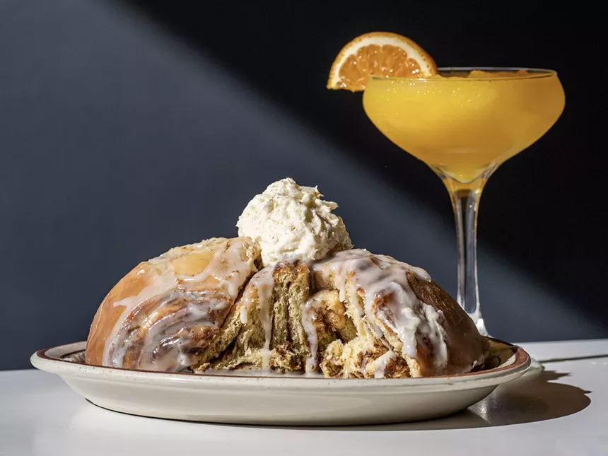 A giant HashTAG cinnamon roll plated next to a mimosa